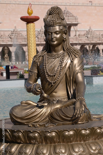 Foto A bronze statue of a Hindu sage sits in a meditative pose on a lotus base with a decorative flame in the background