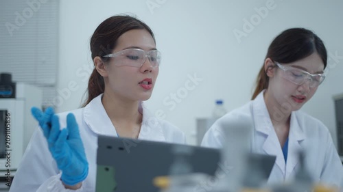 Two female scientists collaborating and discussing research results on a tablet computer in a modern laboratory