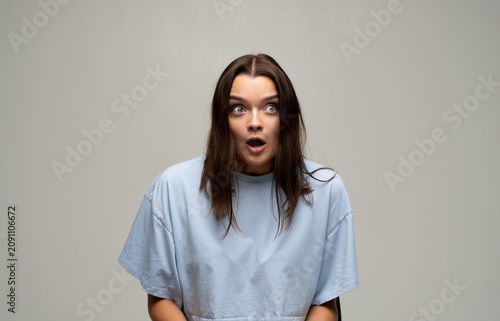 Fotografija Young woman with wide-eyed surprise, expressing shock and disbelief, mouth open