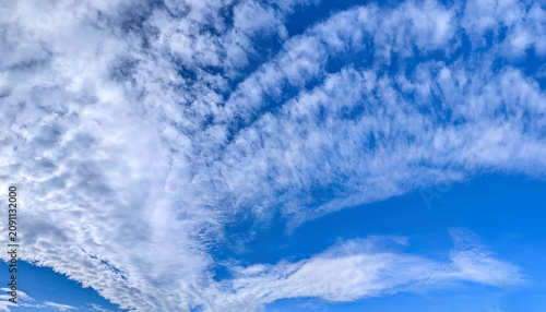 A large cirrus cloud. Clouds flowing lazily like cottony fibers against a clear, serene blue background. The sky speaks of calm, peace, and silence.