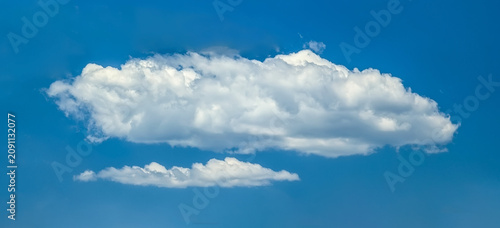 Several cumulus clouds. Cloud flowing lazily like cottony fibers against a clear, serene blue background. The sky speaks of calm, peace, and silence.