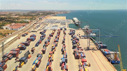 A drone view shows a large container terminal with stacked containers and gantry cranes