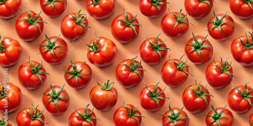 A repeating pattern of fresh red tomatoes with green stems arranged on a soft peach colored background, for a vibrant, food display