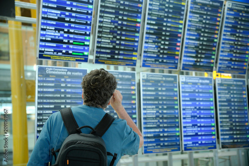 Man looking at airport departure arrival board