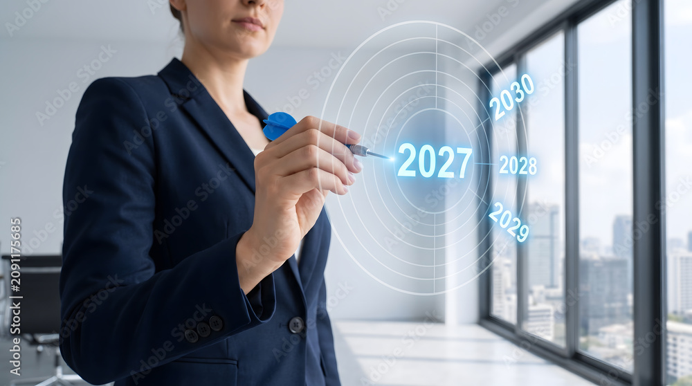 Obraz premium Targeting 2027 business goals concept: Businesswoman aiming a dart at a glowing digital future timeline hologram, 2027 future planning and corporate strategy.