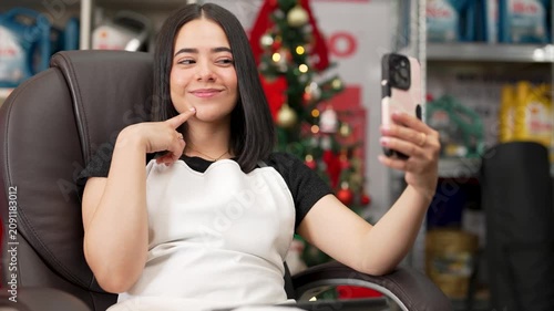 Female hardware store employee owner taking a break to record a video selfie during christmas holidays