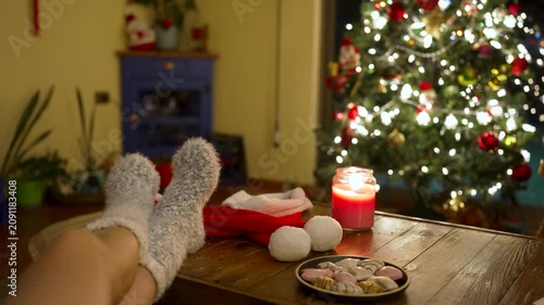 Person wearing fluffy socks resting in a living room with a decorated christmas tree in background
