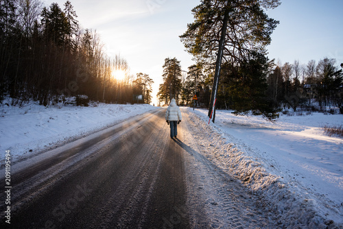 Obraz na płótnie A Lone Walker on an Icy Country Road at Winter Sunset, Sweden
