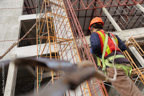 Construction worker in safety gear maneuvering on scaffolding at a building site focusing on engineering and safety practices