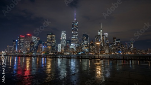 City Skyline at Night With Lights Reflecting on a Wet Surface Near the Water