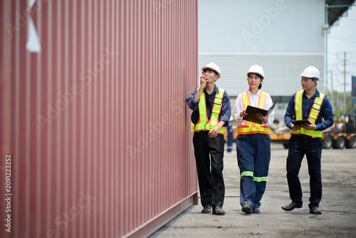 Workers walking and inspecting cargo containers