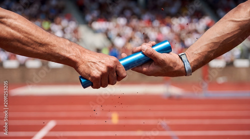 Athletic relay race handover with runners passing the blue baton on the track athletes handover competition teamwork athletics training exercise cooperation