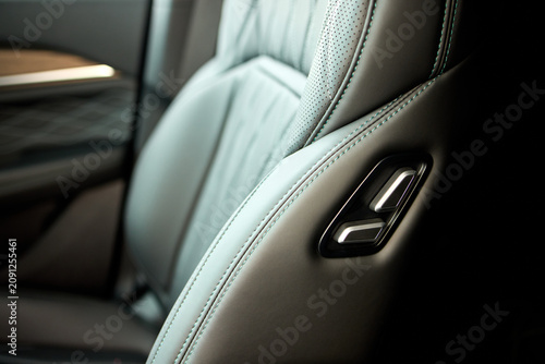 Car seat adjustment control, in interior of a car, with car seat, adjustment lever, with plastic, textile texture, from a close-up perspective, with black, gray accents.