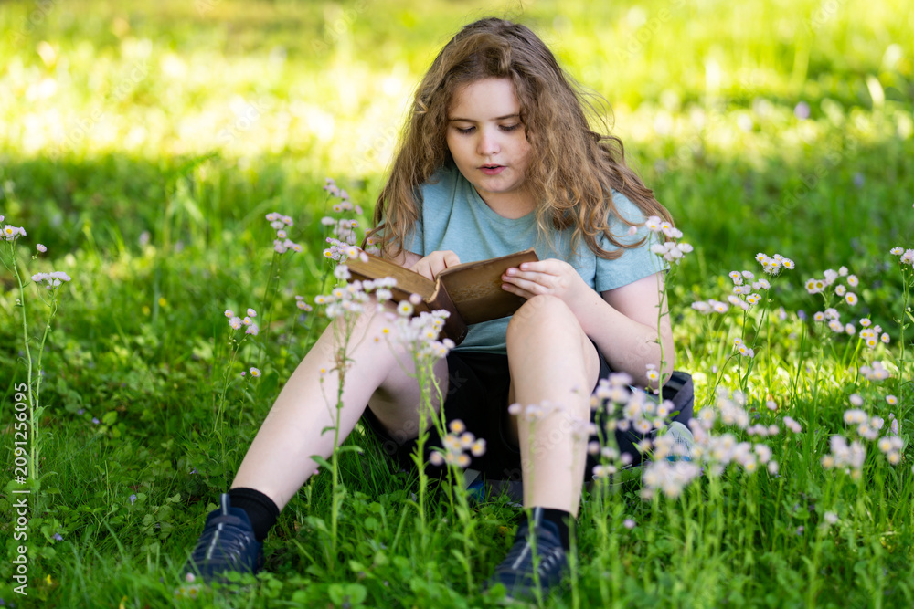 Fototapeta premium Focused expression shows serious reading. Young focused girl studies quietly. Focused kid reads in blurred bokeh. Focused learning creates educational portrait.
