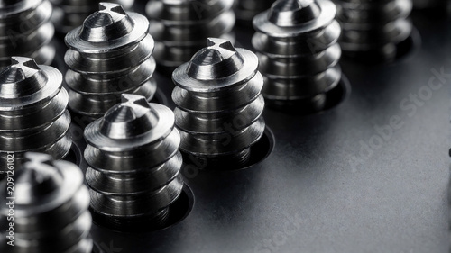 Eine extreme Makroaufnahme zeigt mehrere präzise gefertigte Edelstahlschrauben mit deutlich sichtbaren Gewinden und feinen Metallstrukturen.KI Generiert