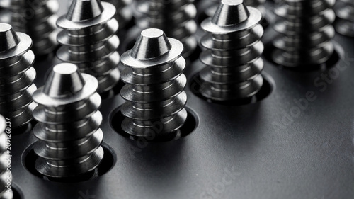 Eine extreme Makroaufnahme zeigt mehrere präzise gefertigte Edelstahlschrauben mit deutlich sichtbaren Gewinden und feinen Metallstrukturen.KI Generiert