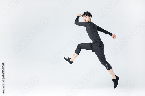 Photography Athletic young man jumping in midair in black sportswear