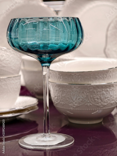 Foto Beautiful blue wine glass with tall stem highlighted against white plates on a l