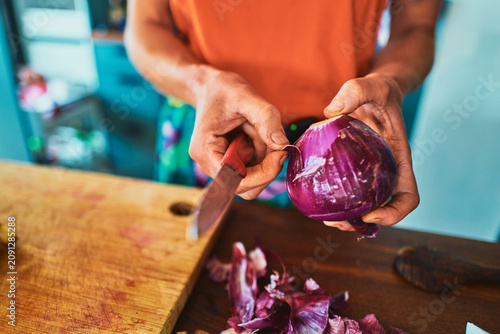 Peeling the skin off a red onion on a chopping board