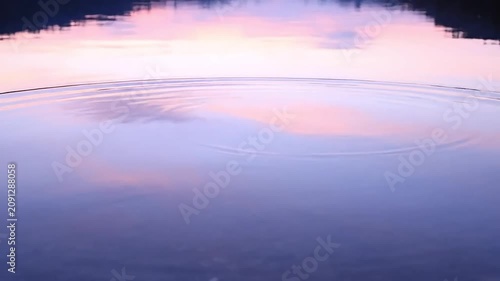 Serene water surface reflecting soft pastel sky at dusk, with gentle ripples.