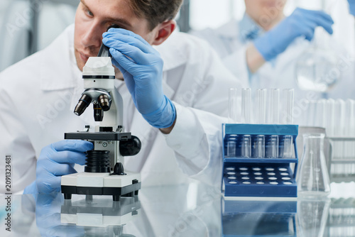 фотографія Young scientist or researcher in protective workwear studying new virus in micro