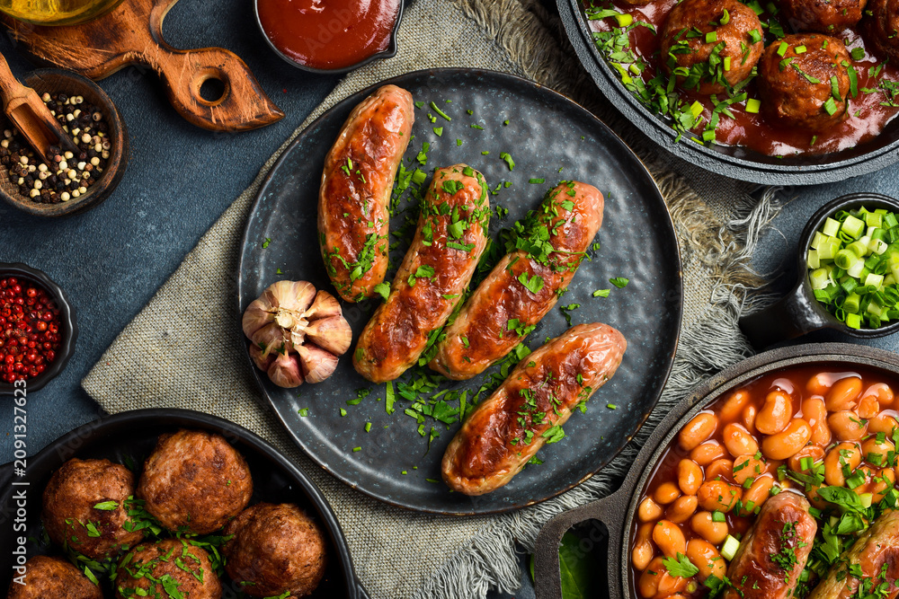 Fototapeta premium Grilled pork sausages with parsley, sauce and garlic. On a stone plate. Close-up.