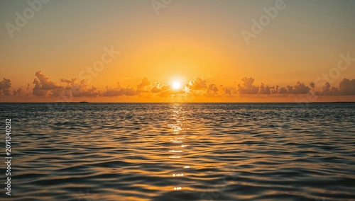 Sun Sets Over the Calm Ocean Creating a Warm Glow on the Water in the Evening