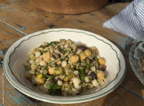 A ceramic plate filled with traditional Cretan fotokollyva, a festive salad made of mixed boiled legumes, wheat and herbs. Authentic Greek gastronomy.