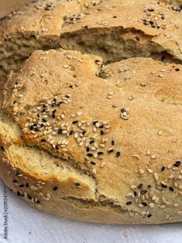Vertical shot of traditional Cretan eftazymo bread crust topped with black and white sesame seeds. Freshly baked homemade rustic loaf details from Crete island, Greece.