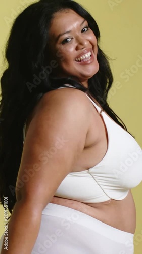 Vertical video: Smiling model posing and turning in studio, wearing white bra high waist underwear
