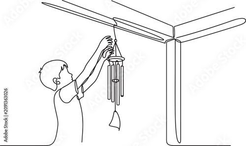 Billede på lærred boy hanging wind chime on house porch