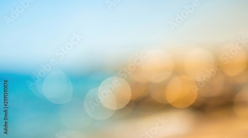 abstract blurred background with blue and golden colors resembling sunny beach or ocean sunset. soft bokeh lights and clear copyspace. banner, website header, summer vacation backdrop.