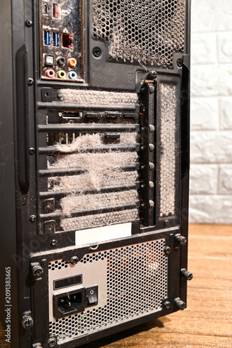 Foto Dust covered desktop computer standing on a wooden floor with a heavily clogged rear panel