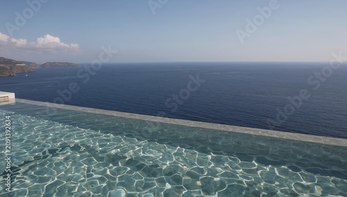Infinity Pool Overlooks Ocean View in Warm Sunlight at Peaceful Coastal Locat...