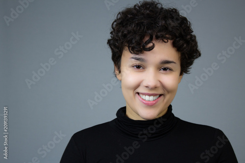 Headshot of a happy young woman with short hair. Horizontal studio portrait with copy space, ideal for gen z, happiness, femininity, and woman self-esteem.