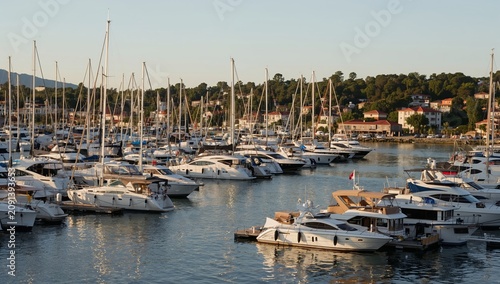 Boats Gather in a Busy Marina During Late Afternoon Light Near a Coastal Town
