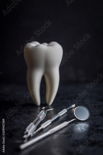 Dental Tooth Model With Stainless Steel Dental Tools and Mirror on Dark Background for Dentistry