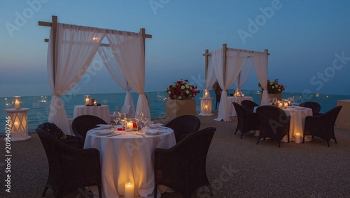 Elegant Dining Setting by the Sea During Twilight With Candles and Flowers on...