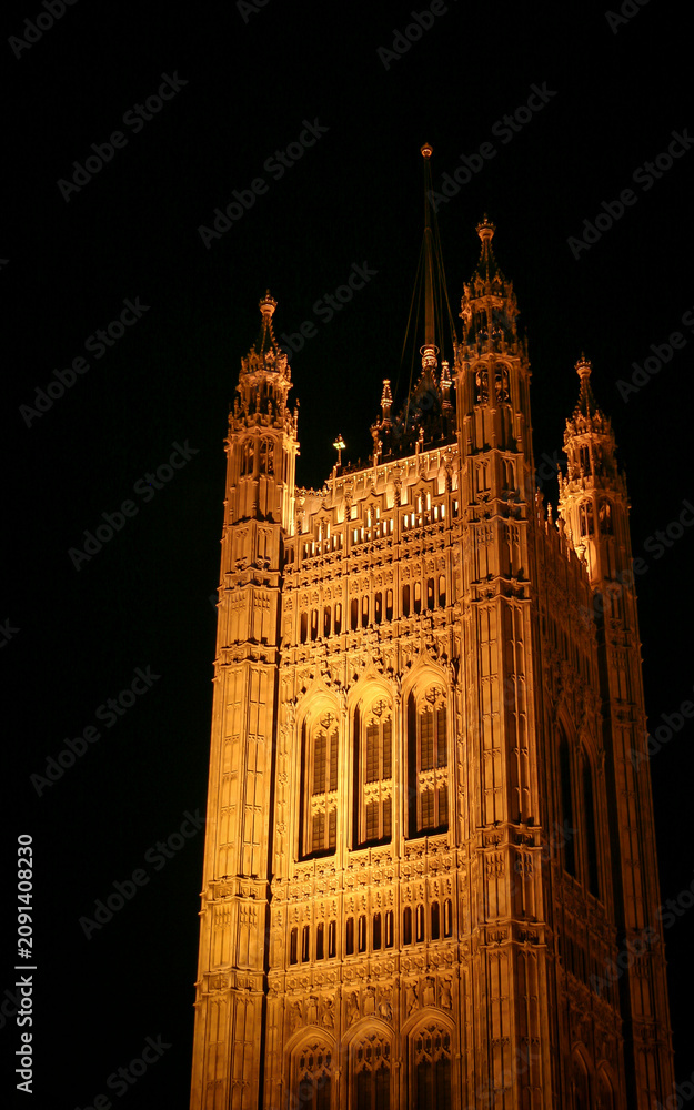 Naklejka premium Central Tower Of Parliament. Low angle view of historic palace architecture illuminated against a dark night sky.