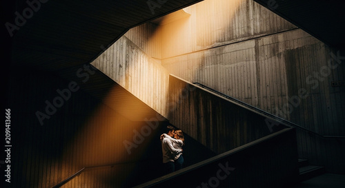 Couple Embracing in Sunlit Urban Stairwell