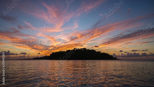 Sunset Over an Island With Colorful Clouds and Calm Waters in the Evening Sky