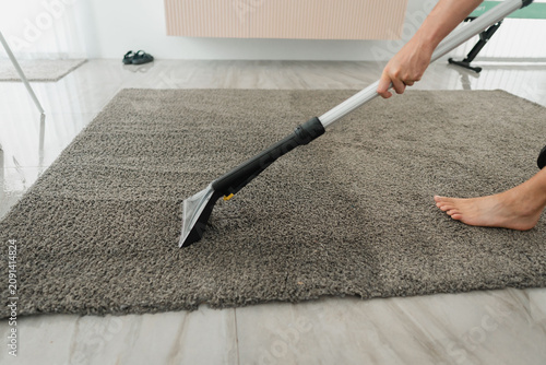 Cuadro en lienzo Handheld upholstery tool cleaning gray shag rug on tiled floor beside radiator w