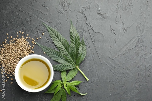 Cuadro en lienzo Hemp oil, seeds and leaves on black table, flat lay