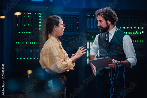 Картината върху платно It specialists collaborating on network solutions in a data center, discussing s