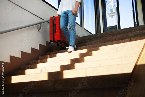 Fotografie passenger is descending station stairs carrying a red suitcase
