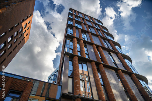 Canvas Print Modern facades of apartment buildings made of terracotta brick, glass, and metal against a bright blue sky in Moscow's ZIL district