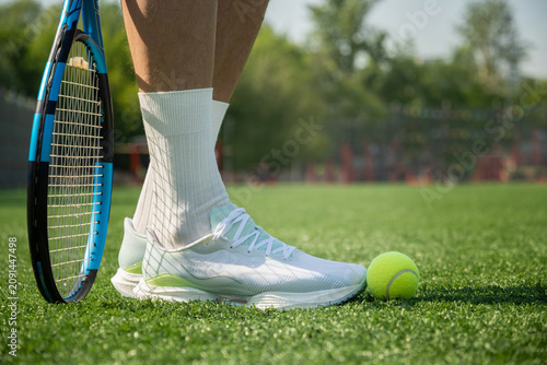 Close up of tennis shoes racket and ball on outdoor sports court