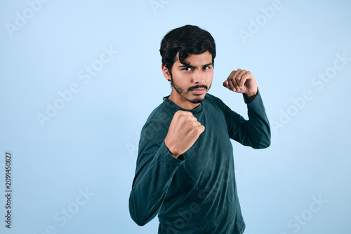 Foto portrait of young latin man in fighting pose on blue background in Mexico Latin