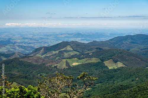 Panoramic and distant view of green valleys and rolling mountains under summer morning sunny clear and light clouded blue sky in Monte Verde, Camanducaia, Minas Gerais - Brazil