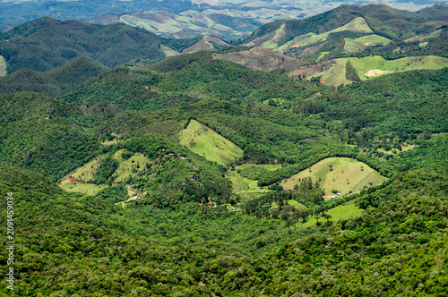 Lush green mountains and rural valleys forming a vast natural landscape as saw from Pedra Redonda granite rock under clear daylight in Monte Verde, Camanducaia, Minas Gerais - Brazil
